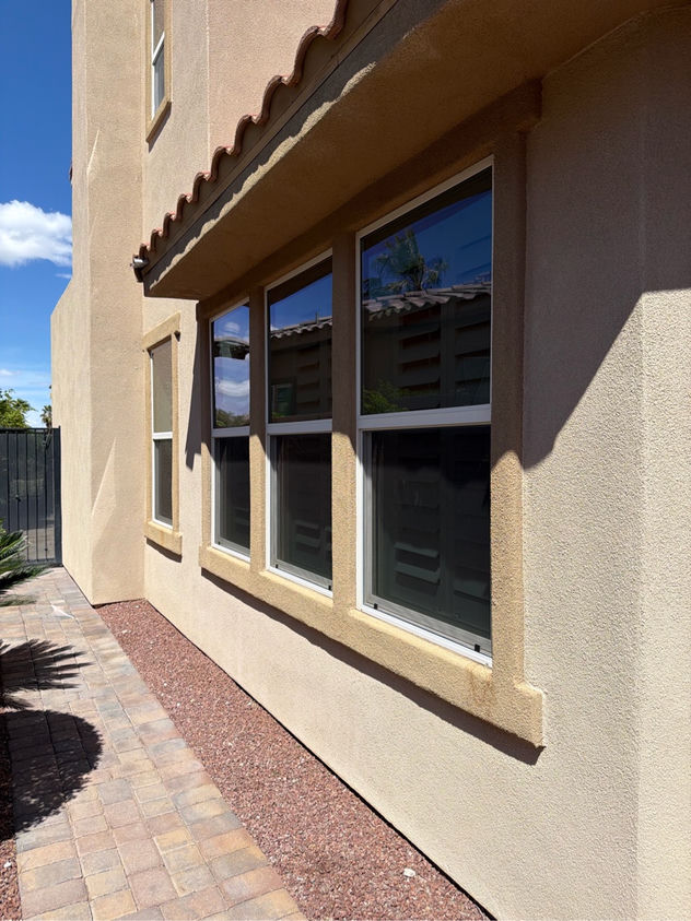 Custom window screens installed on a multi-window Las Vegas stucco home with desert landscaping
