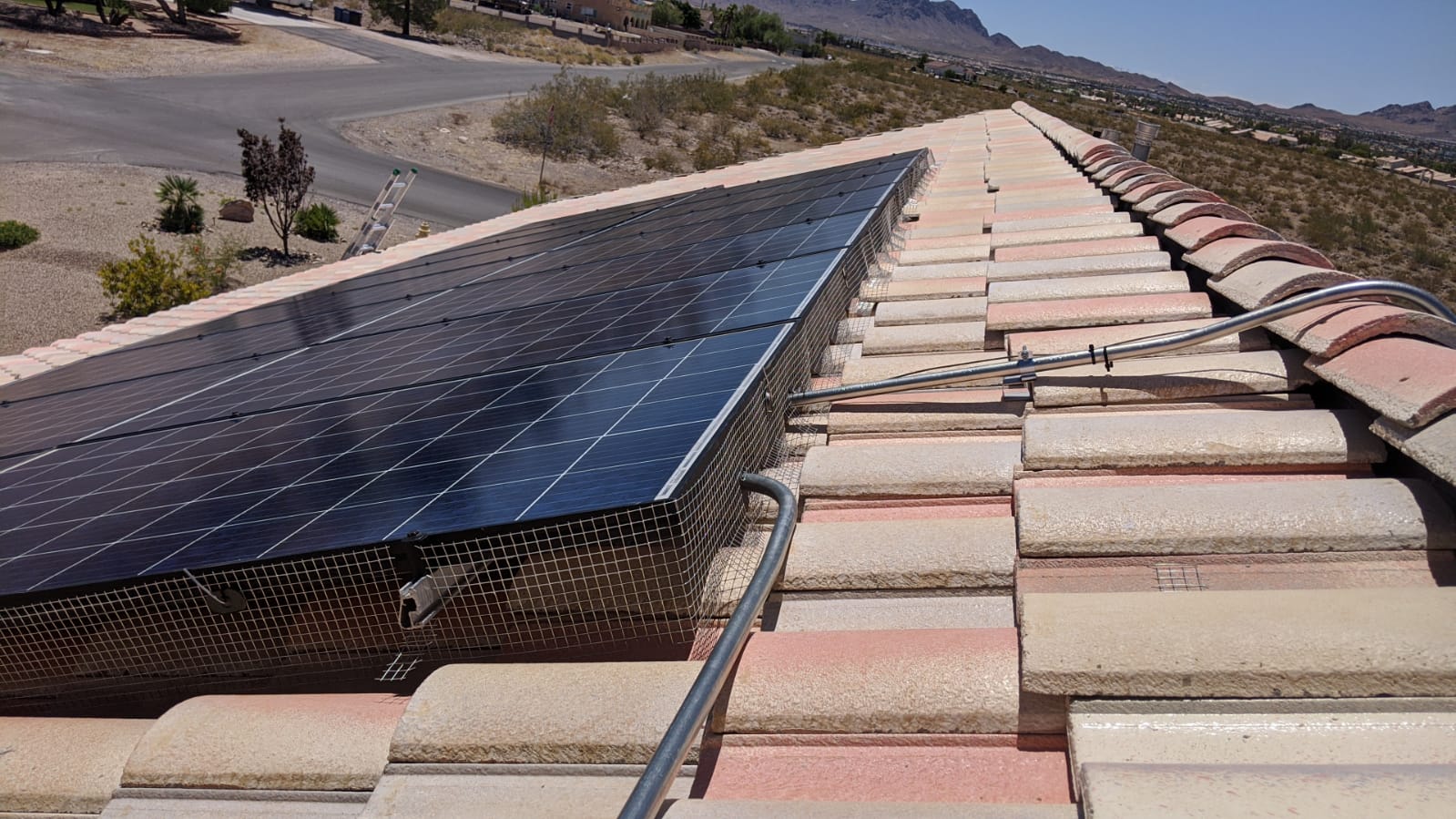 Completed pigeon guard mesh around a solar panel array on a Las Vegas tile roof