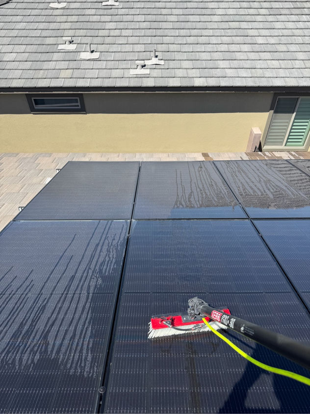 Close-up of a soft brush cleaning a solar panel using purified water on a Las Vegas residential rooftop